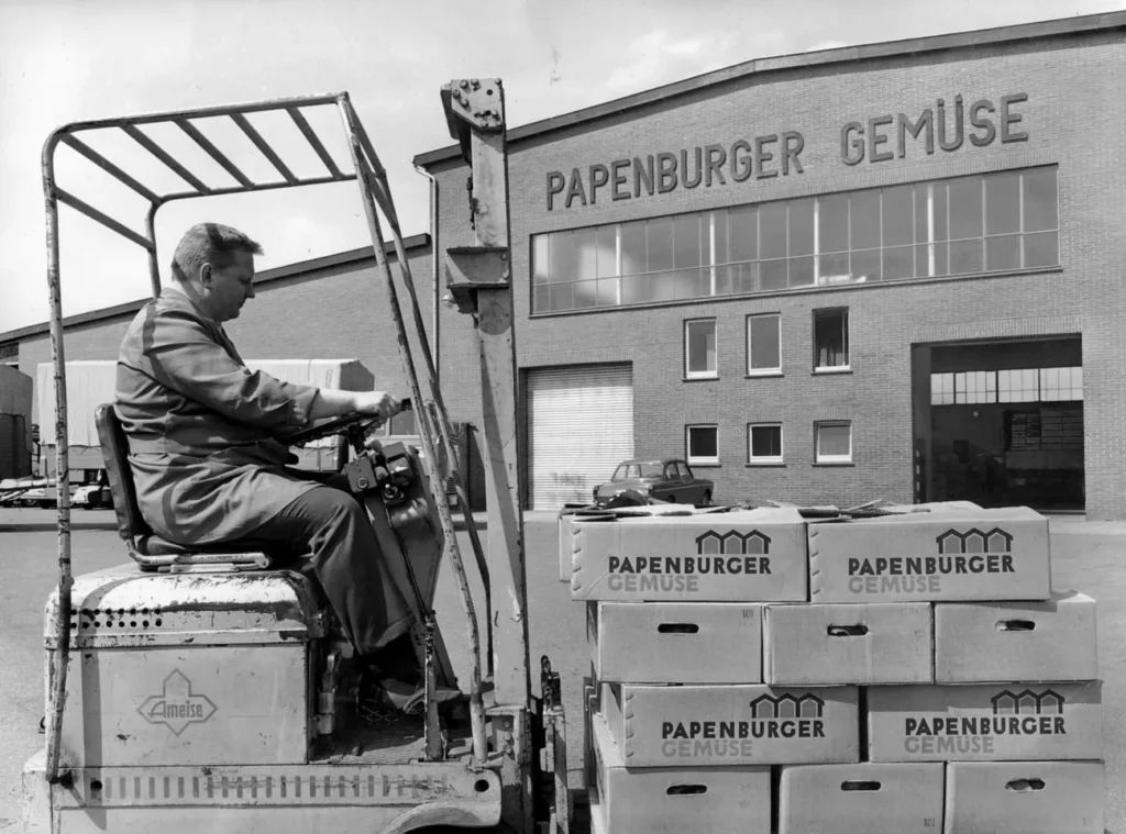 Ein Arbeiter fährt einen Gabelstapler mit gestapelten Kartons der Papenburger Gemüse vor einem Fabrikgebäude.
