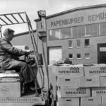 Ein Arbeiter fährt einen Gabelstapler mit gestapelten Kartons der Papenburger Gemüse vor einem Fabrikgebäude.