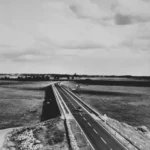 Schwarz-Weiß-Foto einer zweispurigen Autobahn durch flaches Emsländer Kulturland, aufgenommen von einer Brücke.