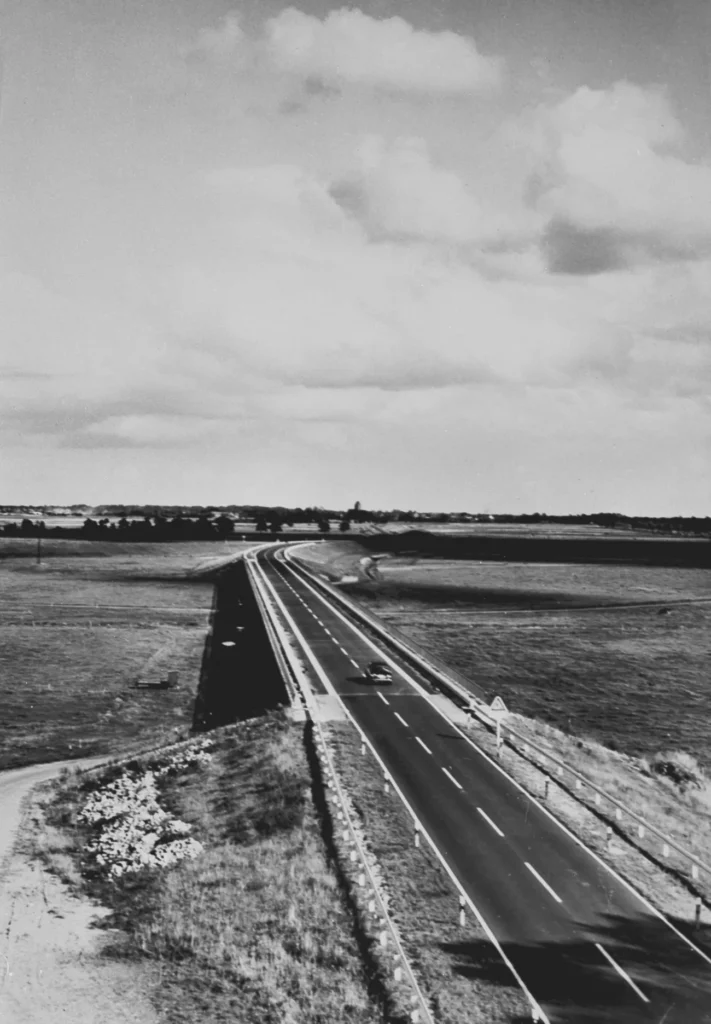 Schwarz-Weiß-Foto einer zweispurigen Autobahn durch flaches Emsländer Kulturland, aufgenommen von einer Brücke.