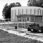 Schwarzweißfoto des Klärwerks Haren mit rundem Betonbau, Beschriftung 1966–1967 und technischen Anlagen im Vordergrund.