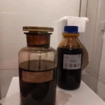Zwei dunkle Glasflaschen mit Rohöl: eine historische Flasche mit Etikett 'Erdöl aus dem Feld Brashar' und eine moderne BP-Flasche mit der Aufschrift 'Rohöl'.
