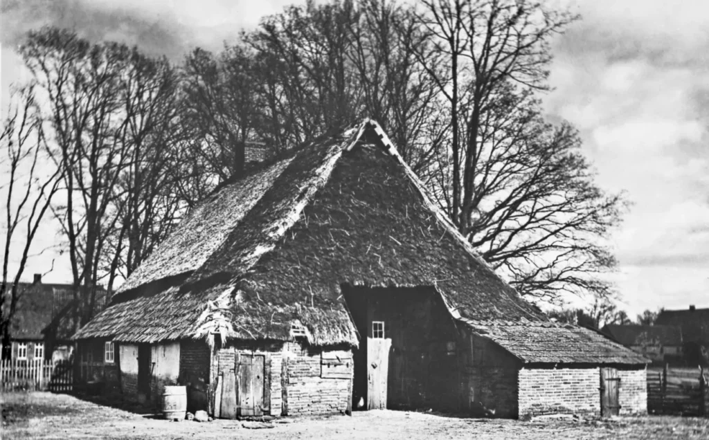 Historisches Schwarzweißfoto eines verfallenen emsländischen Bauernhofs mit Reetdach und Backsteinwänden aus der Emslanderschließungszeit.