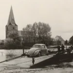 Ein VW Käfer überquert auf einer Seilfähre die Ems, im Hintergrund eine Kirche mit spitzem Turm, 1950er Jahre.