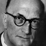 Schwarz-Weiß-Porträtfoto von Richard Hugle, einem älteren, kahlen Mann mit runder Hornbrille im Anzug.