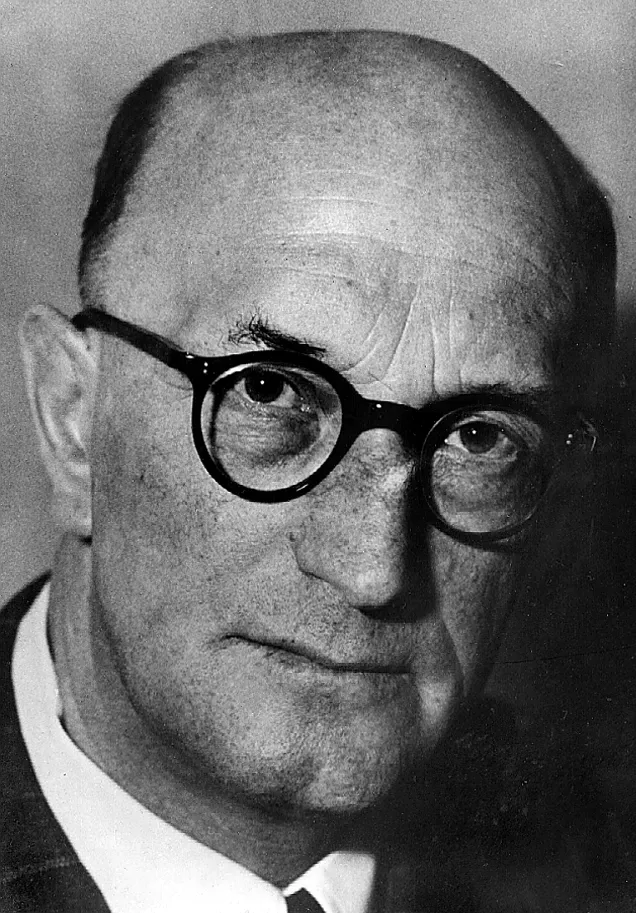 Schwarz-Weiß-Porträtfoto von Richard Hugle, einem älteren, kahlen Mann mit runder Hornbrille im Anzug.
