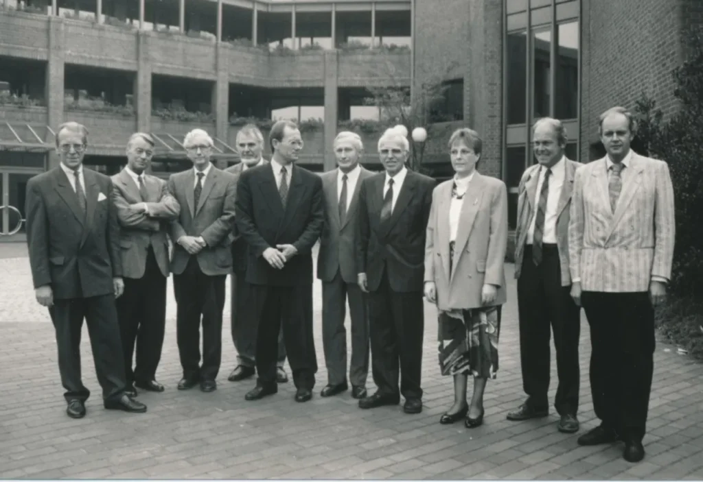 Elf Personen in formeller Kleidung stehen vor einem modernen Backsteingebäude bei der Auflösungsfeier der Emsland GmbH.