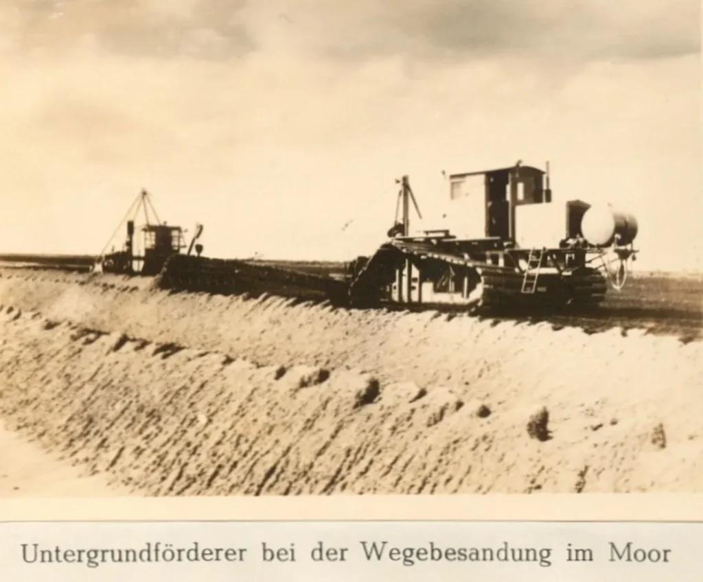 Ein Untergrundförderer auf Gleisketten bearbeitet einen Moorweg im Emsland, ca. 1950er-Jahre.