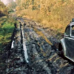 Ein grauer VW Käfer steht auf einem tief aufgewühlten, matschigen Feldweg in der Grafschaft Bentheim, ca. 1950er Jahre.