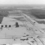 Luftaufnahme der Raffinerie Lingen mit Öltanks, Gleisanlagen und gerodeter Sandfläche, umgeben von Wald, um 1951.