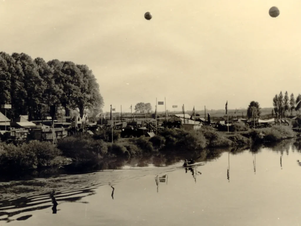 Historische Schwarzweißaufnahme der Emsland-Ausstellung 1951 in Meppen mit Zelten, Fahnen und Fesselballons an der Ems.