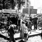 Besucher besichtigen Motorräder auf der Emsland-Ausstellung 1951 in Meppen, im Hintergrund Firmenschilder regionaler Händler.