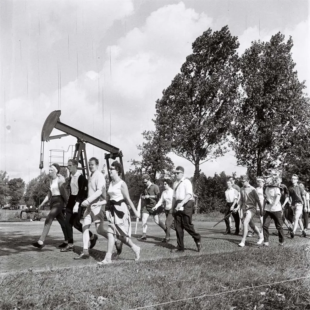 Gruppe von Menschen wandert 1961 an einem Öl-Pumpjack vorbei bei der deutsch-niederländischen Bohrturmwanderung.