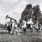 Gruppe von Menschen wandert 1961 an einem Öl-Pumpjack vorbei bei der deutsch-niederländischen Bohrturmwanderung.