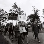 Kinder marschieren mit handgemalten Schildern, darunter 'Berlin – Weg mit der Mauer', bei der Bohrturmwanderung 1961.