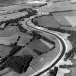 Luftaufnahme eines begradигten Flusslaufs mit befestigten Ufern inmitten landwirtschaftlicher Felder im Emsland.