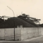 Große Kartoffelhaufen hinter einer Betonmauer mit Förderanlagen auf dem Gelände der Emsland-Stärke GmbH.