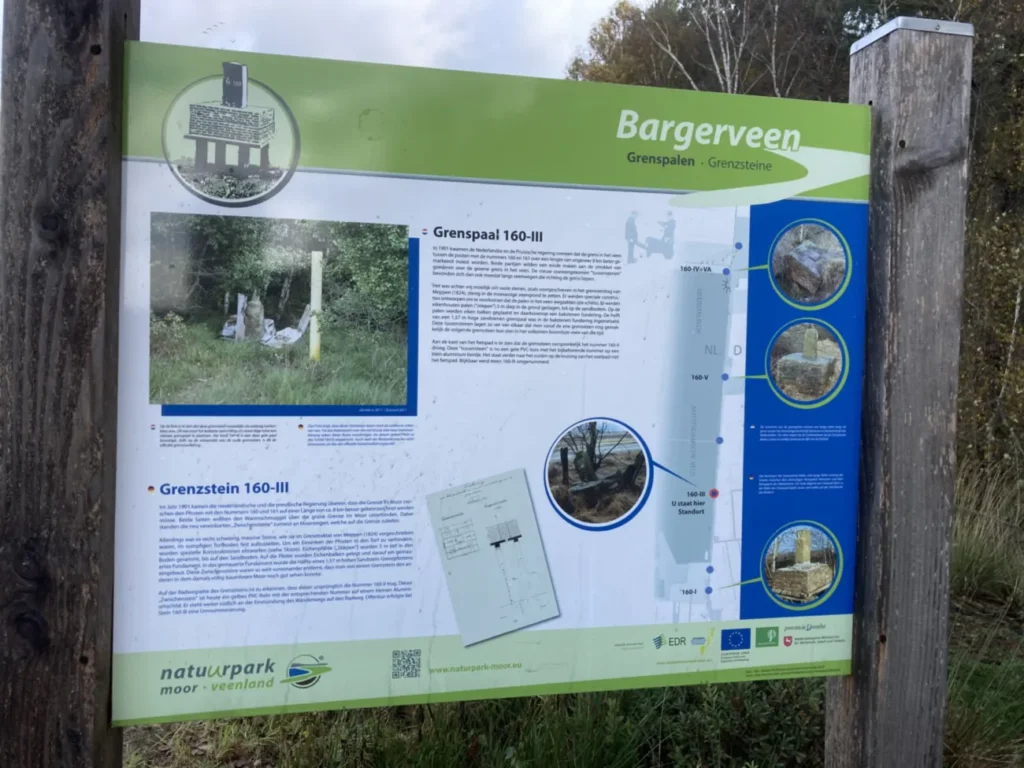 Zweisprachige Infotafel im Naturpark Moor-Veenland über historische Grenzsteine zwischen Nederland und Deutschland.