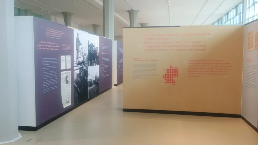 Museumsausstellung mit lila und beigen Tafeln zur deutsch-niederländischen Grenzgebietsdebatte nach dem Zweiten Weltkrieg.