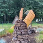Ein Kunstwerk aus gestapelten Torfblöcken mit einem gelben Pflugschild symbolisiert die Moorkolonisierung im Emsland.