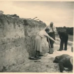 Mehrere Personen untersuchen eine Bodenprofil-Wand bei einer archäologischen Ausgrabung im Emsland.