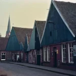 Historische Straßenzeile in Neuenhaus mit markanten Spitzdächern, Backsteinbauten und Kopfsteinpflaster, im Hintergrund ein Kirchturm.