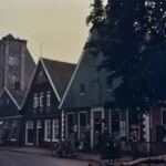 Historische Straßenszene in Neuenhaus mit traditionellen Giebelhäusern, Kirche, Oldtimer und Passanten in den 1950er Jahren.