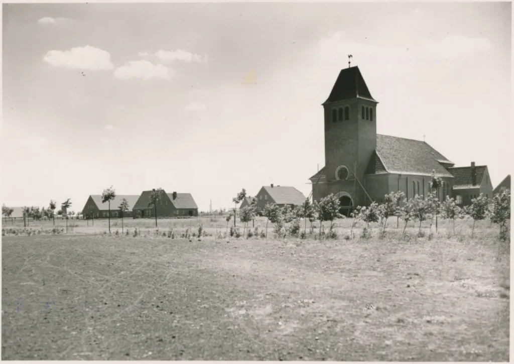 Blick auf die neue Siedlung Hasselbrock mit Backsteinkirche und jungen Bäumen auf unbefestigtem Gelände, um 1950.