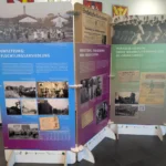Drei Ausstellungstafeln zur Geschichte des Emslandplans mit historischen Fotos und deutschen Texten über Flüchtlingsansiedlung und NS-Zwangsarbeit.