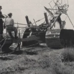 Drei Arbeiter bedienen den holländischen Tiefpflug Gigant bei der Moorkultivierung, historische Schwarzweißaufnahme.