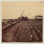 Historische Aufnahme von Torfabbaumaschinen auf einem weitläufigen, gefurchten Torffeld im Emsland.