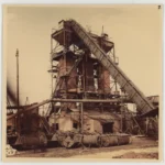 Historische Schwarzweißfoto einer mehrstöckigen Industrieanlage mit Förderbändern und Loren zum Torfabbau im Emsland.